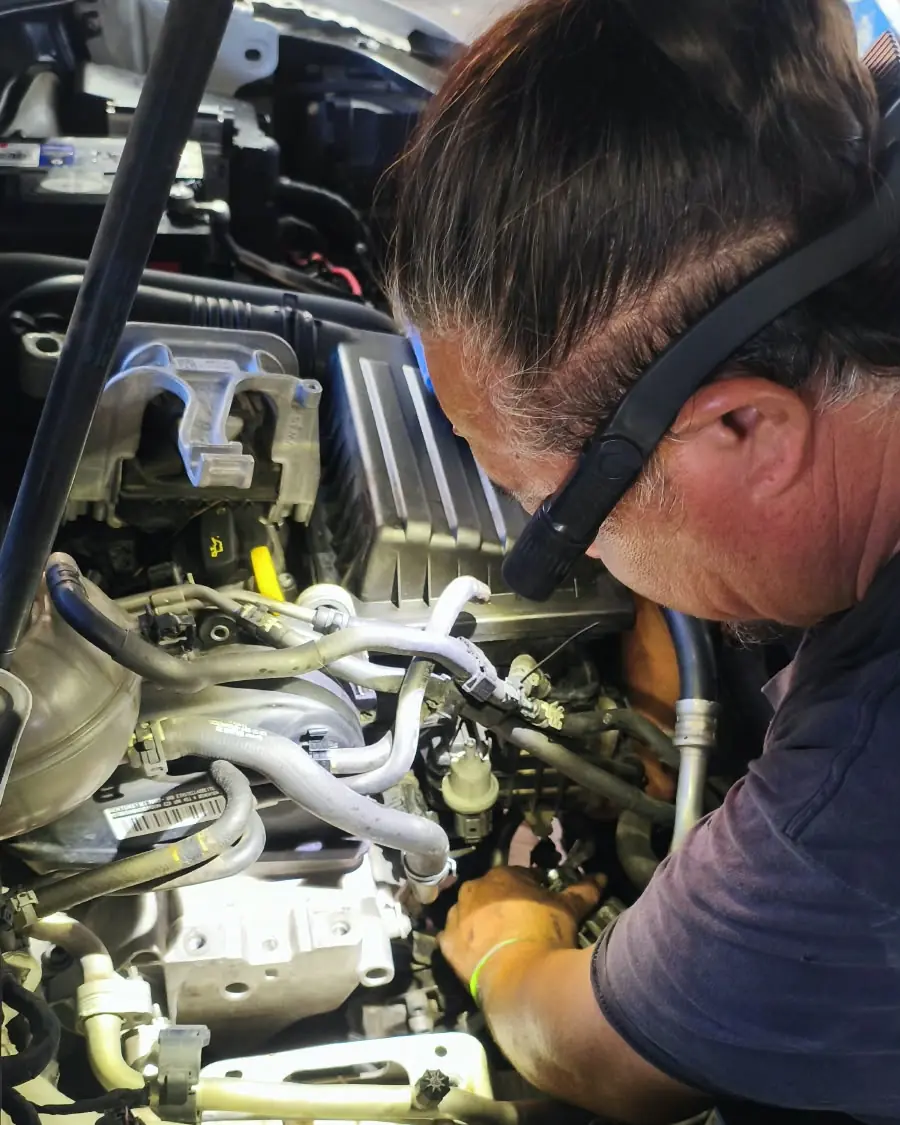 Técnico de SEV revisando el sistema eléctrico en el motor de un vehículo